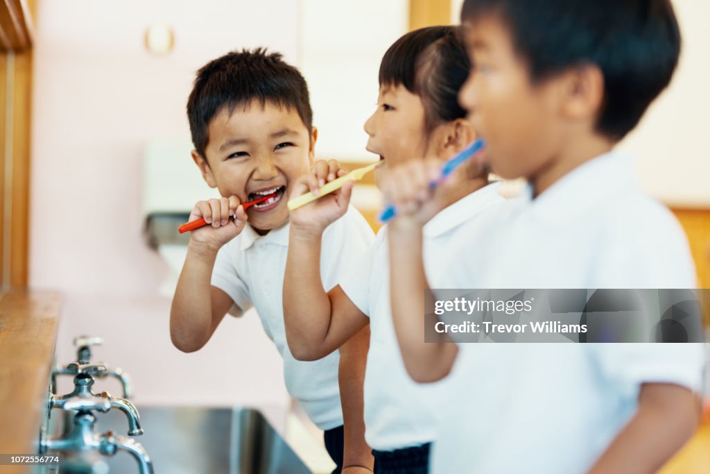 Young children brushing their teeth in a mirror at preschool in Japan