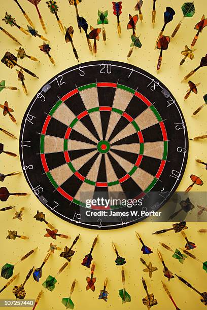 dart board surrounded by darts - darttavla bildbanksfoton och bilder