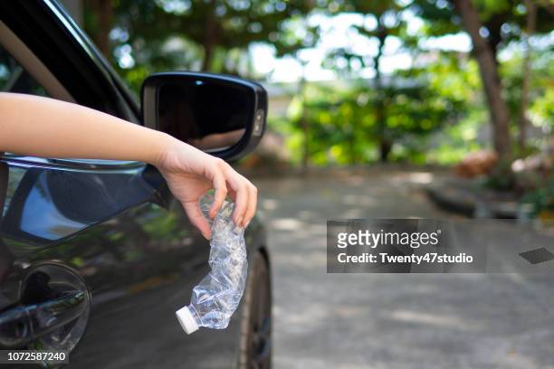 hand throwing plastic bottle on road - throwing rubbish stock pictures, royalty-free photos & images