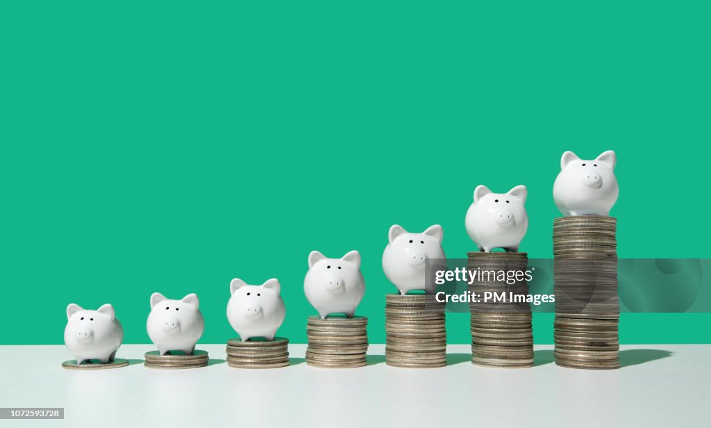 Little piggy banks on ascending stacks of coins