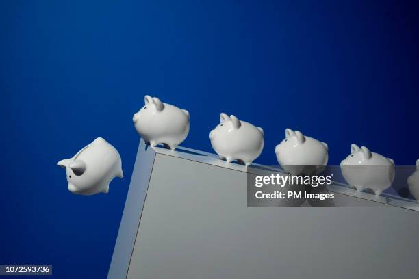 piggy banks going over a cliff - recession stock-fotos und bilder