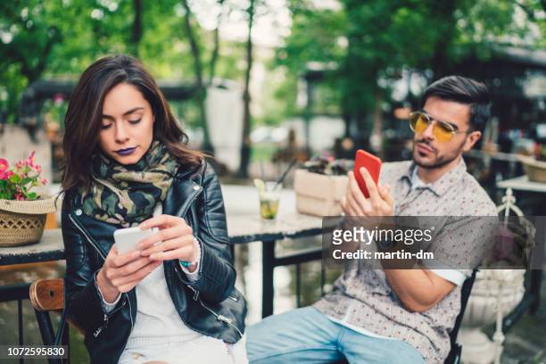 couple in cafe using smartphones and not talking - embarrassed girlfriend stock pictures, royalty-free photos & images