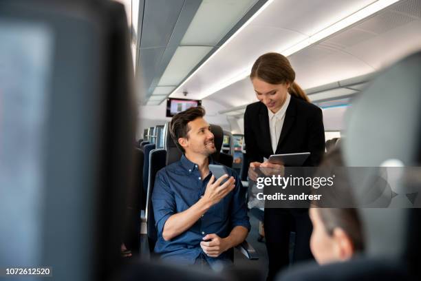 trein verzorger praten met een passagier en haar kaartjes controleren - man woman train station stockfoto's en -beelden