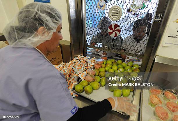 School cafeteria worker hands out fruit and drinks to school children at the Normandie Avenue Elementary School in South Central Los Angeles on...