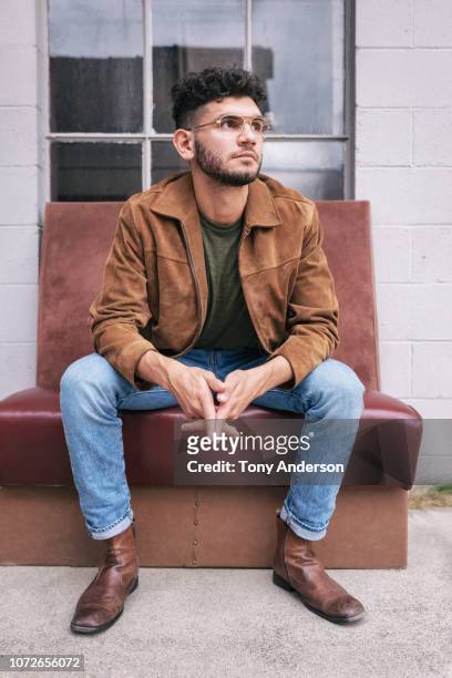 young man sitting outside building - sitzen stock-fotos und bilder