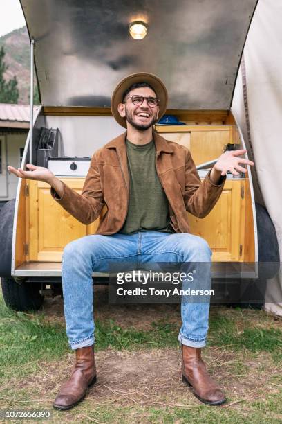 stylish young man sitting on travel trailer - brown jeans ストックフォトと画像