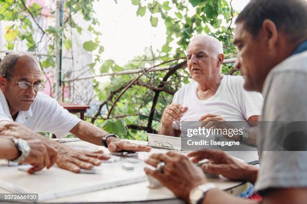gute alte latino freunde spielen domino - nur ältere männer stock-fotos und bilder