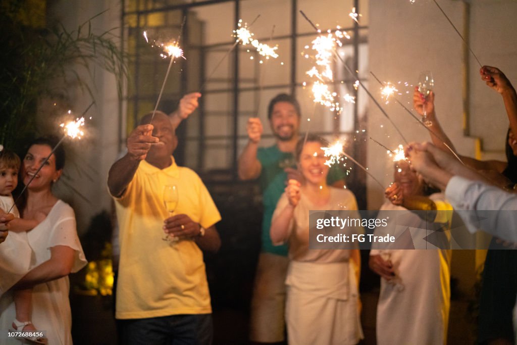 Família e amigos em casa a celebrar a festa de ano novo com Sparkler