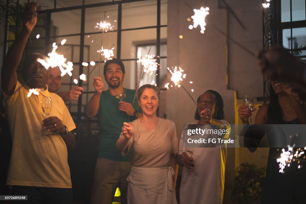 Family and Friends Celebrating New Year Party with Sparkler at Home
