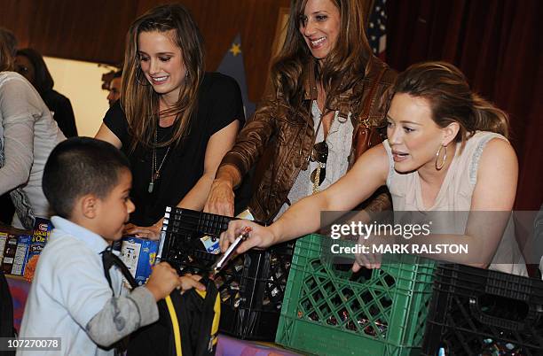 Singer and Actress Hilary Duff hands out food to school children during her appearance for the "Blessings in a Backpack" food program at the...