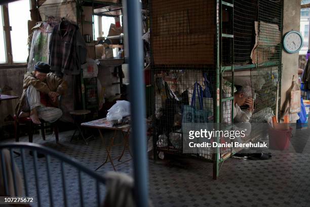 Years-old Tam Wing Dik sits in his cage dwelling as Mr Leung Shu rests near to his cage dwelling on December 01, 2010 in Hong Kong, China. Hong...