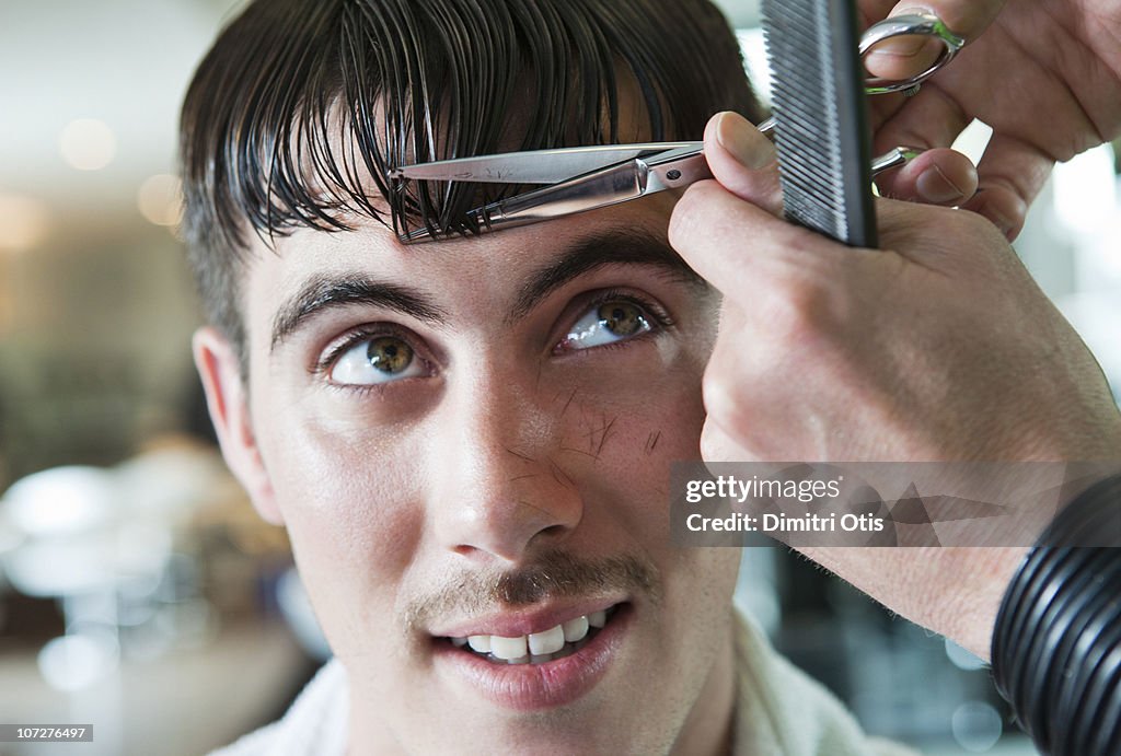 Man having his fringe cut by hairdresser