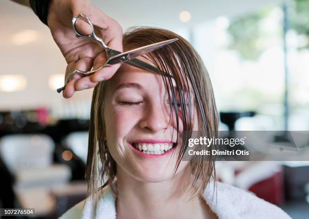 woman with eyes closed having her fringe cut off - peinado fotografías e imágenes de stock