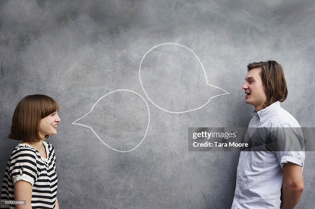Man and woman with speech bubbles on chalk board