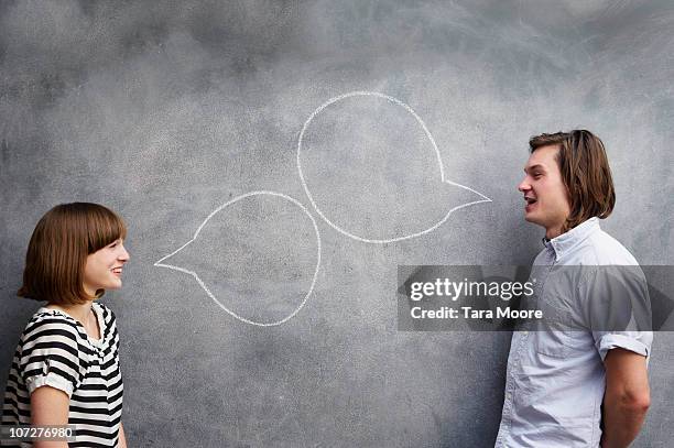man and woman with speech bubbles on chalk board - face to face communication stock pictures, royalty-free photos & images