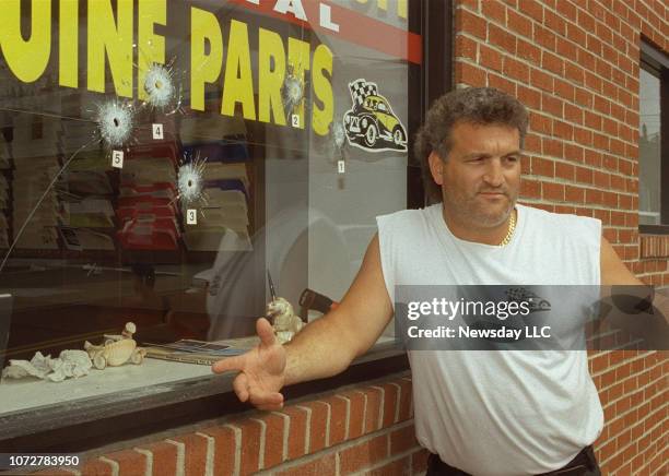 Joey Buttafuoco stands near some of the bullet holes in the front window of his family's auto body shop in Baldwin, New York on June 24, 1994. The...