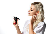 Woman beautician cosmetologist hold Ear Piercing Gun looking at the corner isolated on white