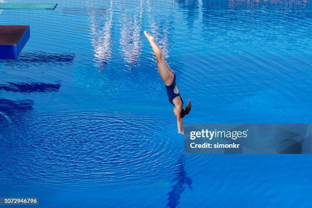 young woman diving in swimming pool - diving stock pictures, royalty-free photos & images