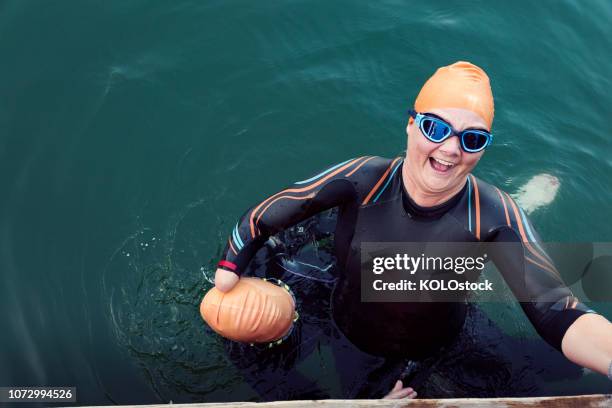 woman helping amputee friend out of the water - open water swimming stock-fotos und bilder