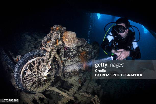 a rusted and overgrown motorbike explored by a scuba diver inside a shipwreck under the sea - boat ruins stock pictures, royalty-free photos & images