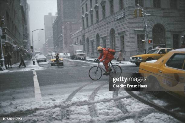 Cyclist crosses a snowy crossroads in New York City, US, winter of 1981.