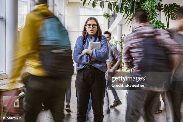 shocked nerdy student among her classmate in blurred motion. - student individuality stock pictures, royalty-free photos & images