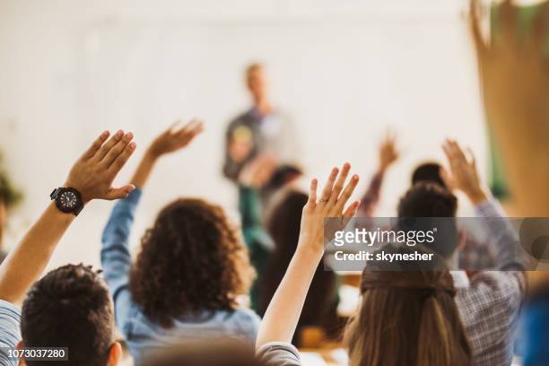 back view of students raising hands on a class. - q and a stock pictures, royalty-free photos & images