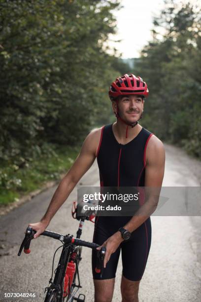 cyclist in lycra walking down a road, bosnia and herzegovina - spandex stock-fotos und bilder