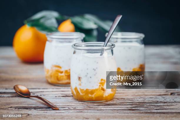 three natural yogurt, orange and chia desserts - yoghurt pot stock-fotos und bilder