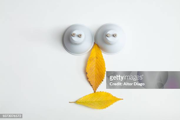 human face formed by a collage of two light bulbs placed upside down and two tree leaves. conceptual nature - face down stock-fotos und bilder
