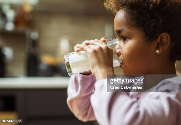 profile view of small black girl drinking milk at home. - drink milk stock pictures, royalty-free photos & images