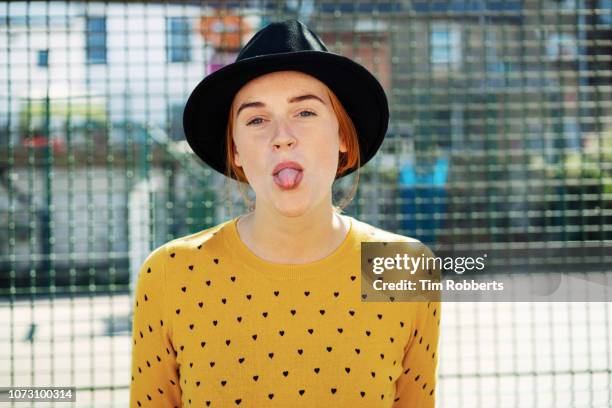 young woman sticking her tongue out - hipster stock-fotos und bilder