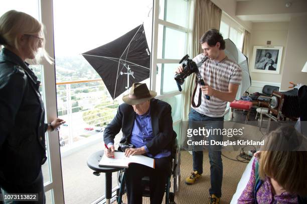 Behind-the-scenes view of Italian film director Bernardo Bertolucci during a photo shoot, Los Angeles, California, November 2013. He autographs a...