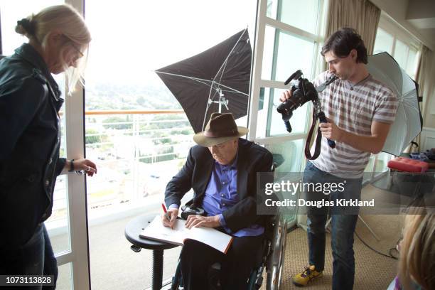 Behind-the-scenes view of Italian film director Bernardo Bertolucci during a photo shoot, Los Angeles, California, November 2013. He autographs a...