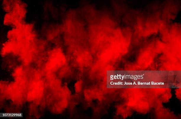 explosion by an impact of a cloud of particles of powder and smoke of color red and black  background. - vapore foto e immagini stock