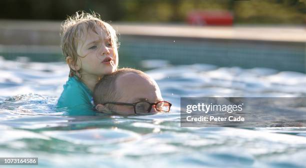 dad swimming with daughter on his back in swimming pool - water glasses ストックフォトと画像