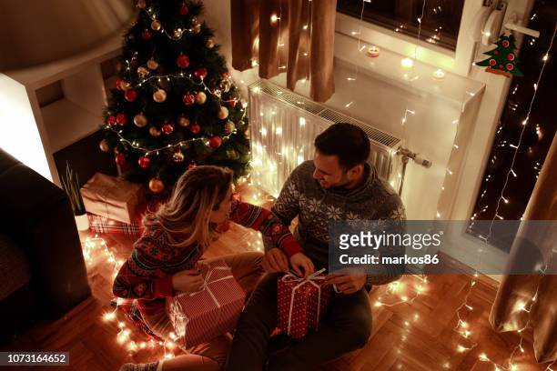 loving couple exchanging gifts at christmas eve - the girlfriend stock pictures, royalty-free photos & images
