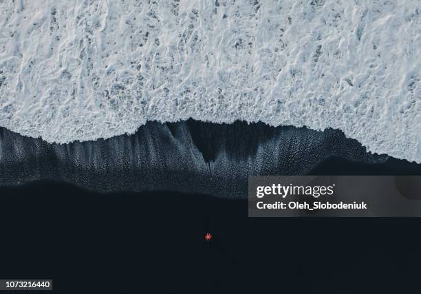 luftaufnahme der frau am schwarzen sandstrand in island - black sand stock-fotos und bilder