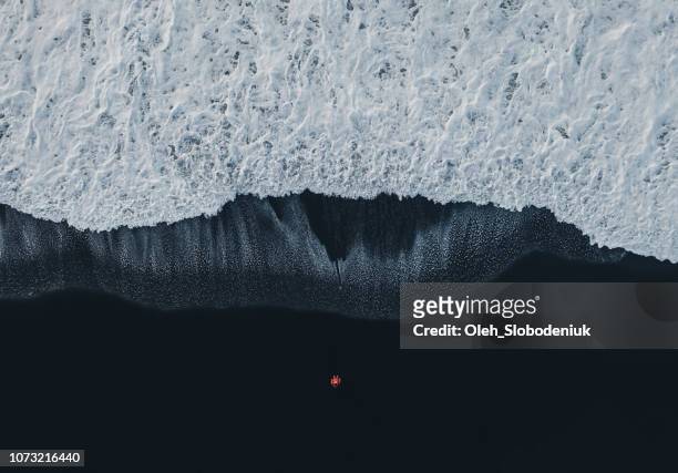 vista aérea de la mujer en la playa de arena negra en islandia - imponente fotografías e imágenes de stock