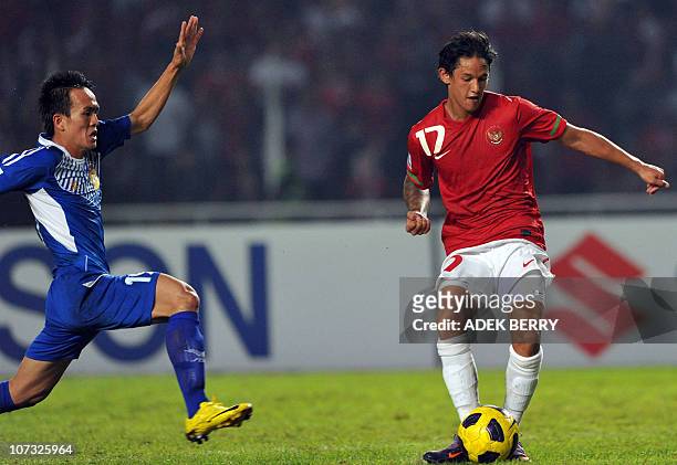 Laos' player Kovanh Namthavixay runs to tackle Indonesian player Irfan Bachdim as he kick to score for his team during the qualification football...