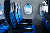 Empty air plane seats. Blue sky and clouds in the window. Airplane interior