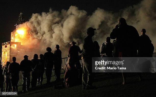 New Orleans residents look on as the traditional Algiers Point Christmas bonfire burns on the Mississippi River levee December 4, 2010 in New...
