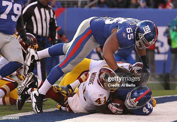Ahmad Bradshaw of the New York Giants scores a touchdown against Kareem Moore of the Washington Redskins as Will Beatty leaps over the pile during...