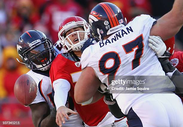 Quarterback Matt Cassel of the Kansas City Chiefs loses the ball as he is pressured by Mario Haggan and Justin Bannan of the Denver Broncos during...