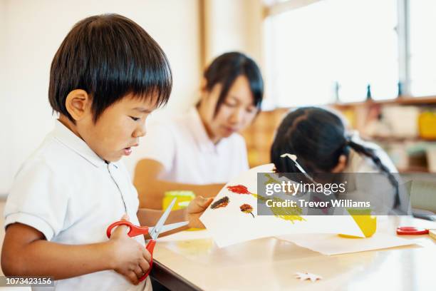 young children doing arts and crafts at preschool in japan - kinder muster fotografías e imágenes de stock