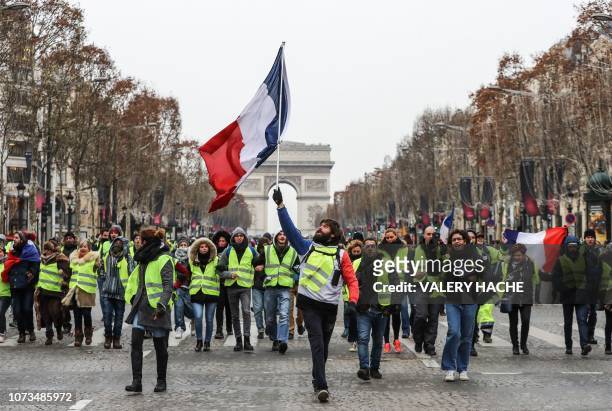 Protester wearing a yellow vest waves the French national flag during a demonstration against rising costs of living blamed on high taxes on the...