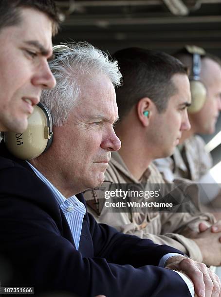 Secretary of Defense Robert Gates watches flight operations from "Vulture's Row" with Lt. Lucas Mixon and Lt. Ben Boysinger December 6, 2010 aboard...