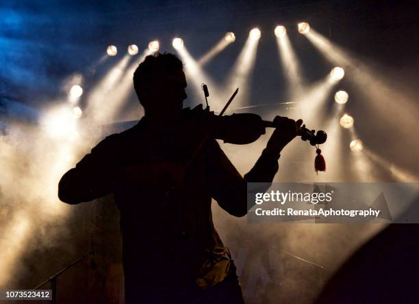 silhouette of a man on stage playing the violin - classical fotografías e imágenes de stock