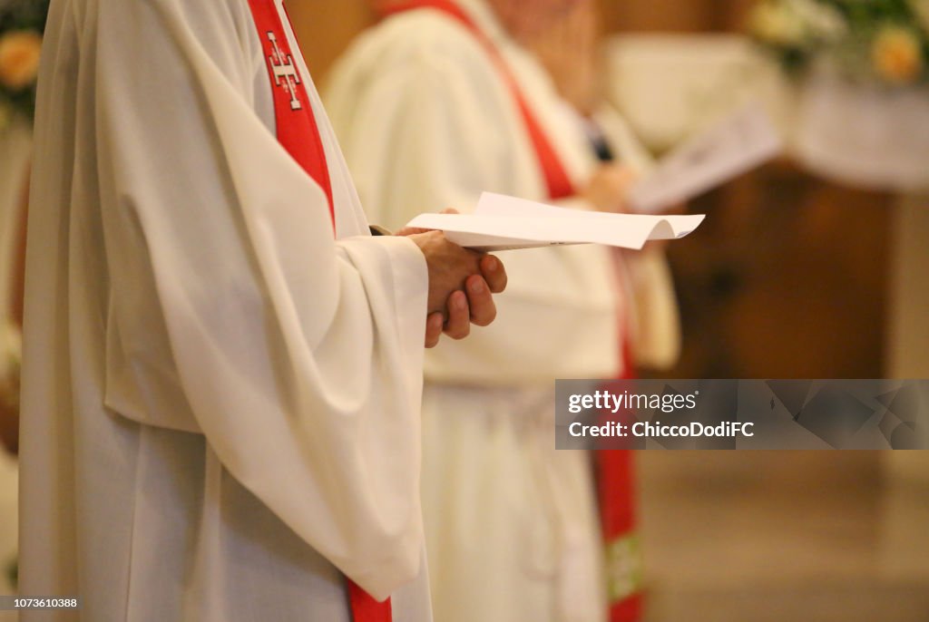 Priest with hands joined in prayer during Holy Mass in church