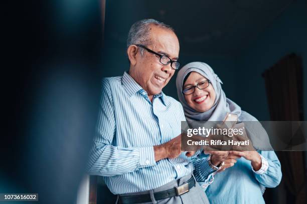 senior asian couple looking at smartphone - malay lover stock pictures, royalty-free photos & images